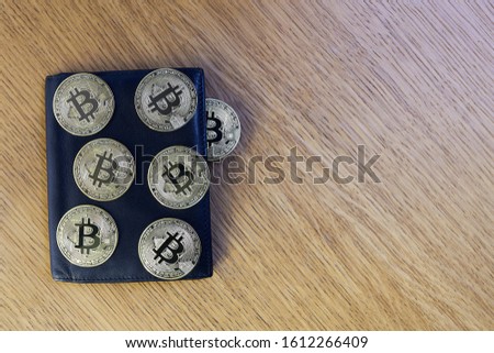 Bitcoin in the black leather wallet on the wood table. money and cryptocurrencies