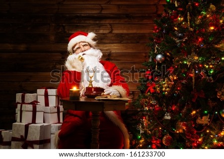 Santa Claus talking over phone in wooden home interior 