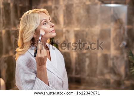 Lady applying a layer of powder to her face