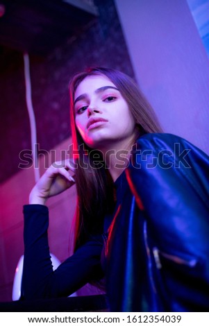 Young beauty girl posing in pink neon light. Model face. Leather jacket