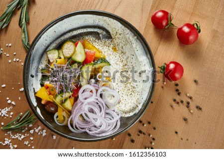 Classic Greek salad with tomatoes, onions, cucumber, feta cheese and black olives with olive oil on a white plate on a wooden background. Top view