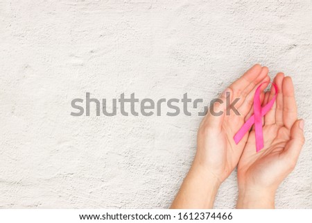 Woman's hand and pink ribbon for world cancer day 
