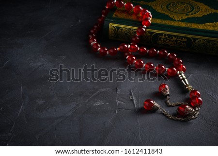 Faith in Islam concept. The Islamic holy book, Quran or Kuran, with rosary beads or “tasbih” on dark background. Landscape orientation.