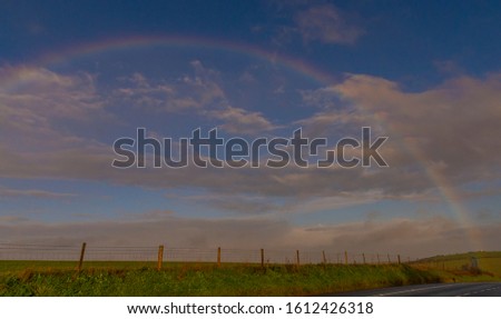 Rainbow going over the field beside the road