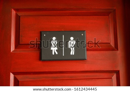 Medium shot of man and lady toilet signs. Restroom funny signs hanged on the wooden red door. Men and women WC sign for the washroom