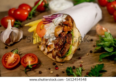 Greek gyros wrapped in pita breads on a wooden background Royalty-Free Stock Photo #1612454548