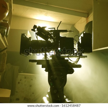 Mystical silhouette of a movie camera in the sun's rays of light from the window. Camera on a tripod in standby mode
