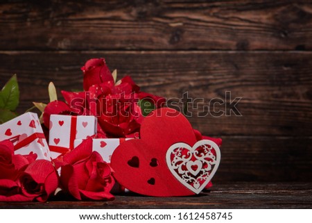 Bouquet of red roses, decorative hearts and gift boxes on dark brown wooden background with copy space. Valentine's Day. Wedding Day. Design element for romantic greeting card and invitation