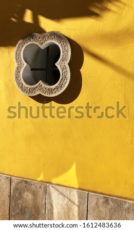 Old yellow wall and beautiful window, shadows on yellow wall