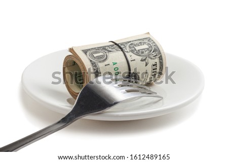 Several American dollar bills rolled up and tied up on white saucer with fork. Roll of money wrapped in elastic band on a white isolated background. Usd money wad, bundle of usa cash.
