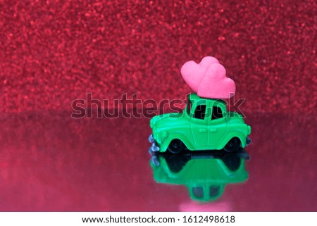 Toy car with two hearts on a red glitter background. Copy space for text. Valentine's Day Blank