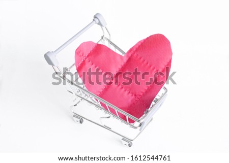 Red heart as a symbol of love, in a shopping trolley, the concept of buying a heart for money for Valentine's Day. Commercial promotion, copy space.