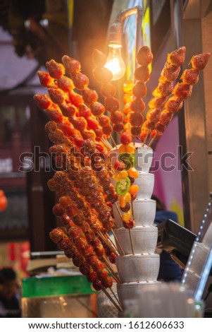 Chinese famous traditional snacks of candied fruit called tanghulu in chinatown street,which consists of fruits covered in hard candy on bamboo skewers