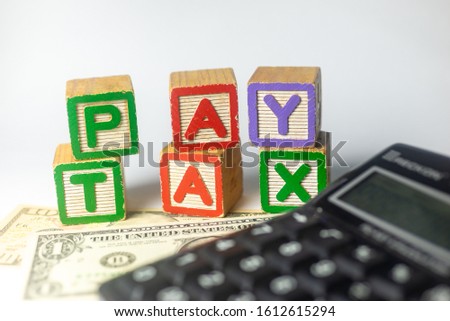 Pay Tax - American Dollars - individual tax concept with toy alphabet blocks. White background, shallow depth of field, selective focusing.
