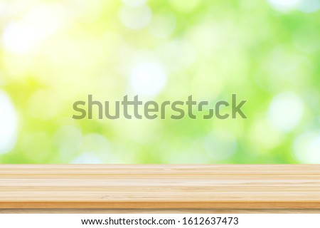 Empty wooden table or shelf with 
Blurred image of abstract circular green bokeh from nature background,  Ready for product display montage.
