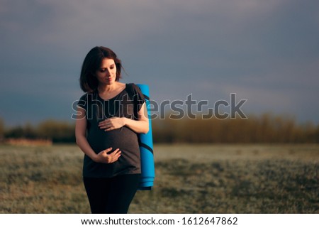 Pregnant Woman with Yoga Mat Relaxing by the Lake. Mother to be planning to do prenatal Pilates in nature
