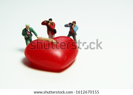 Miniature people figure Model photographer is shooting red hearts.Valentine Concept Selective focus