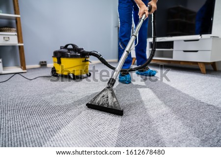 Photo Of Janitor Cleaning Carpet With Vacuum Cleaner Royalty-Free Stock Photo #1612678480
