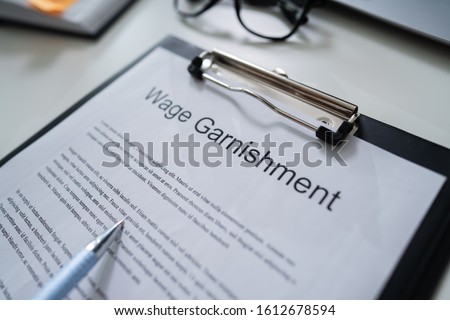 Person Reading  Wage Garnishment Documents At Desk Royalty-Free Stock Photo #1612678594