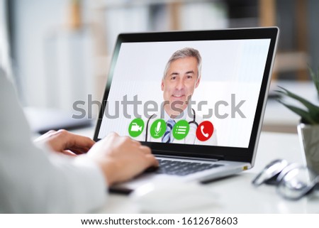 Businesswoman's Hand Videoconferencing With Happy Doctor On Laptop Royalty-Free Stock Photo #1612678603