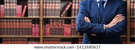Portrait Of Confident Attorney Standing Arms Crossed Against Bookshelf In Office