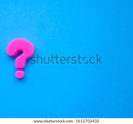 pink question mark on a blue background. Background photo with place for text.