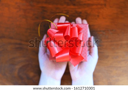 Woman holding red present box in hands for give love valentines day concept / Giving gift boxes with ribbon on wood background