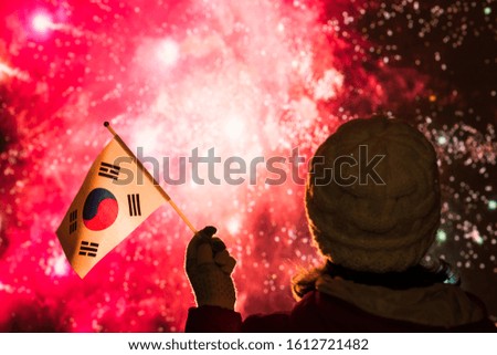 Fireworks at night. Woman in winter clothes with  flag of South Korea on the New Year. 