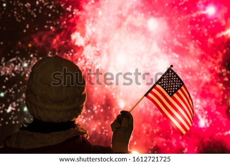Fireworks at night. Woman in winter clothes with American flag.  