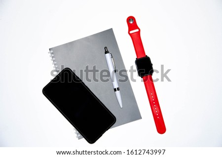 Gray notebook for writing on black background. Ballpoint pen. Smart watch with a red strap. Flat Lai, copies of the paste. View from different sides. Smartphone. Businessmen set kit white background.