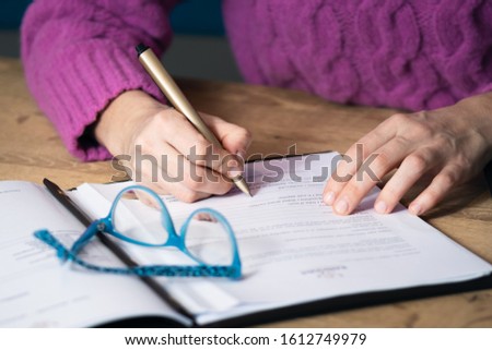 Businesswoman hands signing contract, form, document on wooden table.