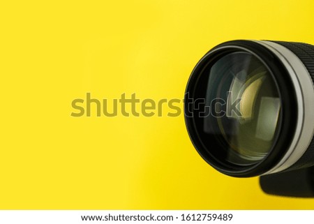 Professional video camera on yellow background, closeup view of lens. Space for text