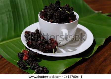 Mulberry berry with banana leaf on wood background