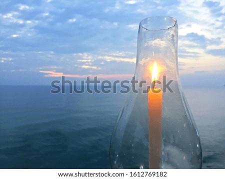 Candle in glass candleholder with Arabian sea background on sunset time, Varkala, India