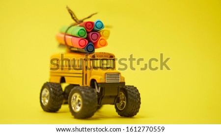 Yellow School bus and felt-tip pens on the roof, back to school concept, yellow background, copy space. education