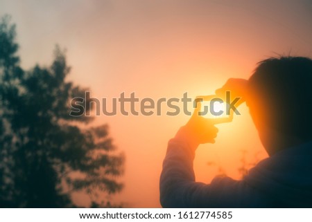 Young man making frame round the sun with his hands in sunrise,Future planning idea concept , copy space,warm retro tone.