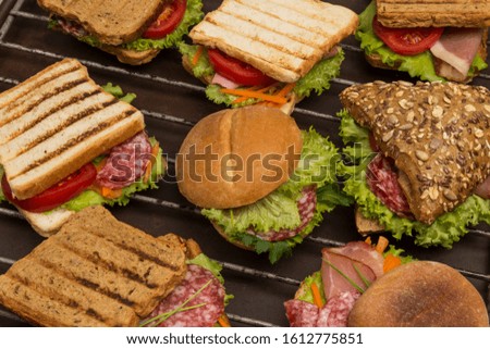 Sandwiches with meat and greens, bun with grains on metal grill. Tasty breakfast. Fast food. Outdoor food concept. top view. Close up
