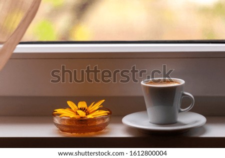 yellow and blue flowers on a table and a cup of coffee