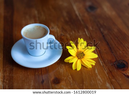 yellow and blue flowers on a table and a cup of coffee