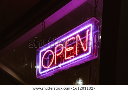 Retro club inscription Open. Vintage electric signboard with bright neon lights. Pink light falls on a brick background."OPEN" restaurant sign in night time with blank copy space, black background.