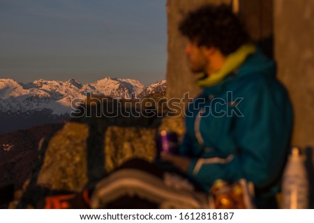 a boy drinking some tea while is watching the mountains during sunset