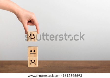 Hand picked up the happy face smile symbol on wooden cube, copy space. Customer Experience Concept