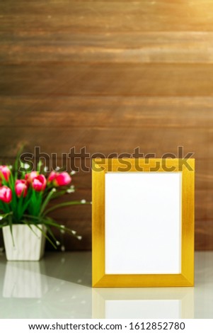 Picture mock up with golden frame and Artificial flower vase bouquet over table with wood wall background