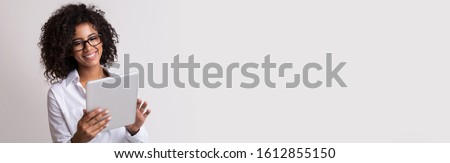 Positive african american business lady using digital tablet, light panorama background, empty space