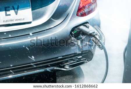 EV Car or Electric car at charging station with the power cable supply plugged in bad weather, winter and snowstorm. Eco-friendly alternative energy concept. Royalty-Free Stock Photo #1612868662