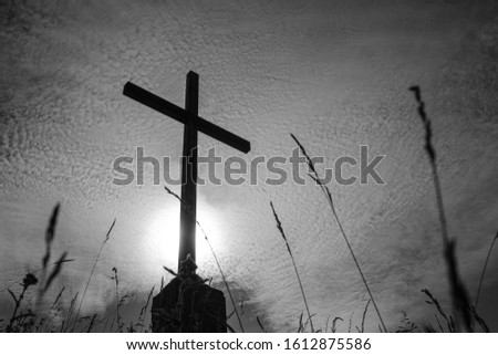 black and white photo of a cross against the sky in small clouds. tragic atmosphere