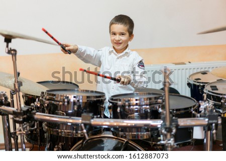 Boy drumming. boy in a white shirt plays the drums. A boy in a white shirt is drumming