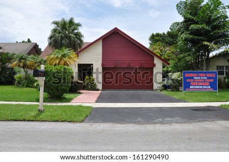 Real Estate For Sale Sign Suburban Back Split Style Home Snout Garage Residential Neighborhood USA Blue Sky Clouds