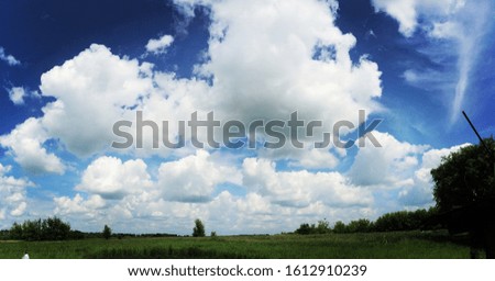 White clouds floating over a green field.