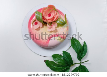 Soft focused shot of mirror glaze cake with pink flowers on white background. Sweet festive pastry for girl or woman day 8 march. Place for text. Spring concept.